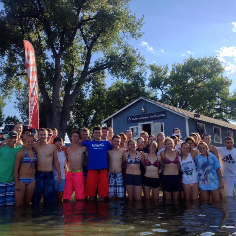 A group posing in the water by the Rocky Mountain Paddleboard building