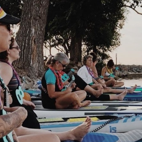 A group of paddlers on boards with ukuleles
