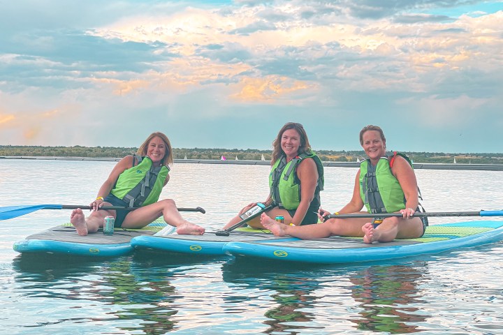group of women paddleboarding during sunset