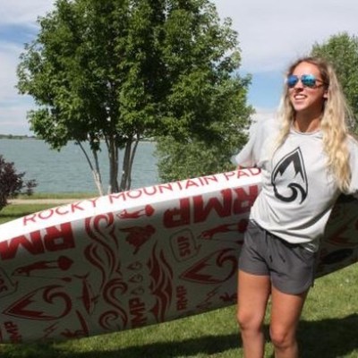 girl holding her paddle board on land