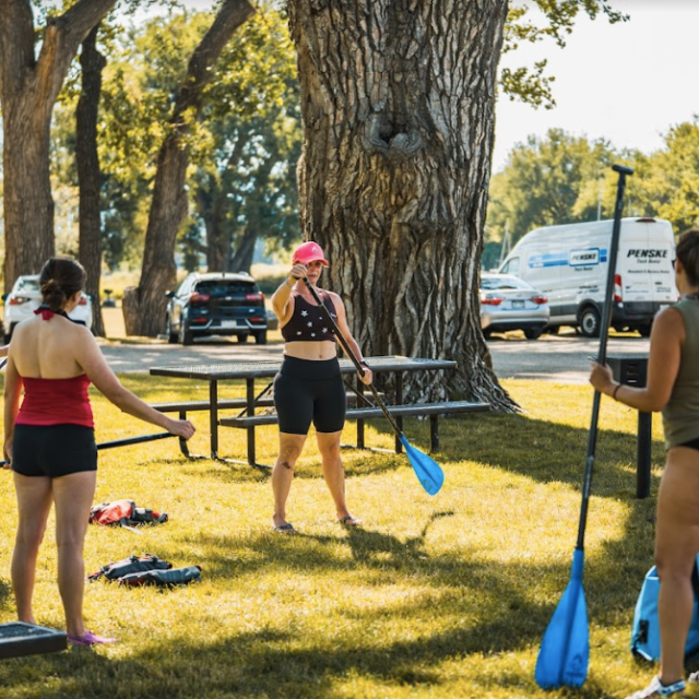 a group of people standing next to a woman at a park